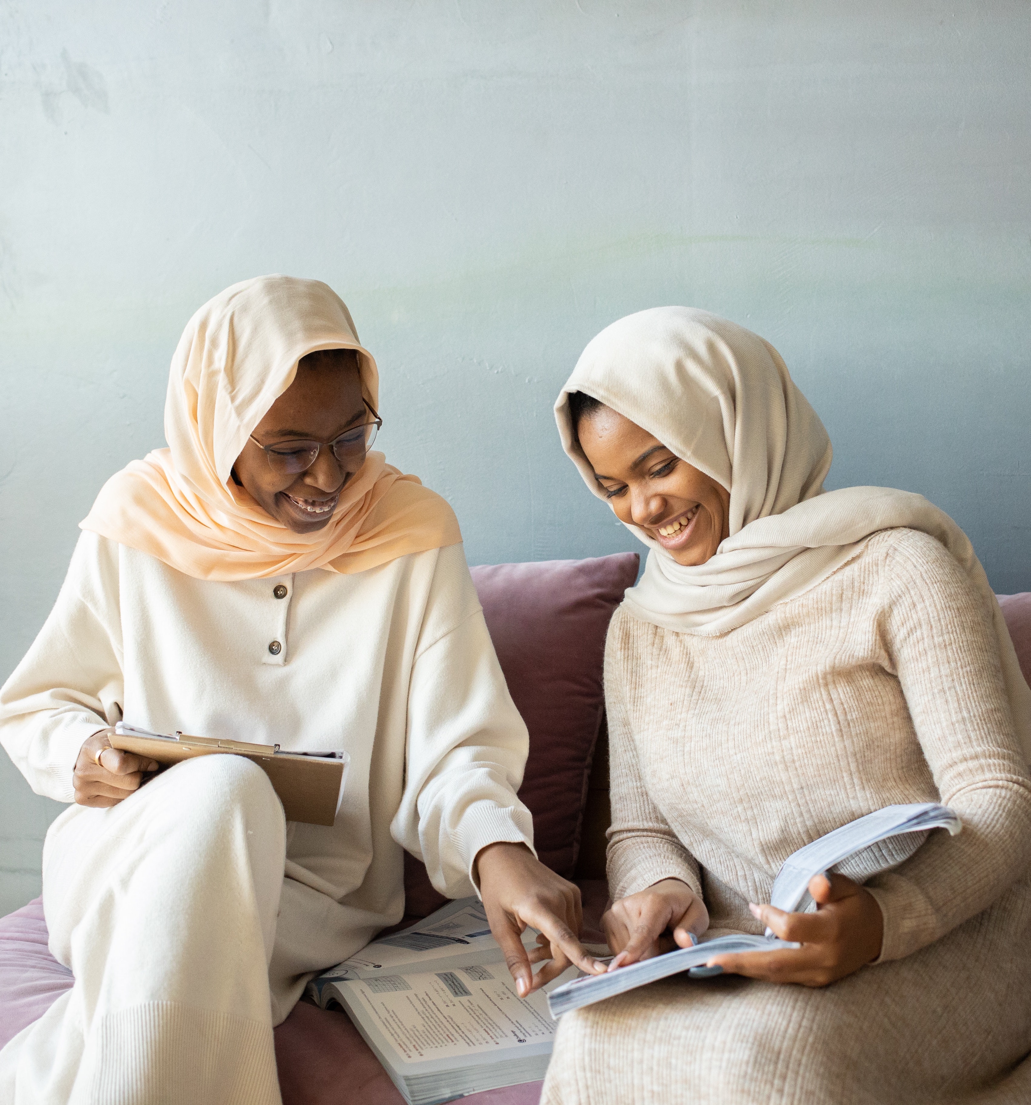 Picture of two female adults smiling pointing at a textbook